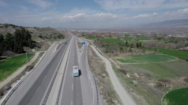 Bir karavanda seyahat eden bir karavan, ilkbaharda bir dron tarafından vurulan tarlalar ve dağlar arasında yol boyunca yolculuk ediyor. Yüksek kalite 4k görüntü