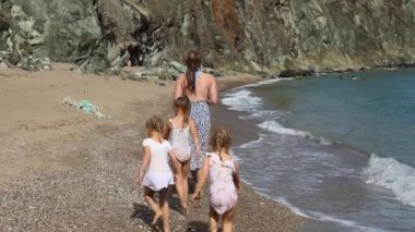 Çocuklu bir aile sıcak denizin sahilinde yürüyor. Yüksek kalite 4k görüntü