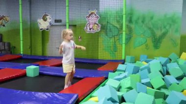 Küçük bir kız çocuk oyun odasında trambolinde zıplıyor. Yüksek kalite 4k görüntü