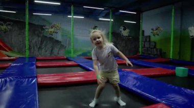 Küçük bir kız çocuk oyun odasında trambolinde zıplıyor. Yüksek kalite 4k görüntü