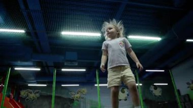 Küçük bir kız çocuk oyun odasında trambolinde zıplıyor. Yüksek kalite 4k görüntü
