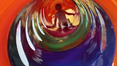 Küçük üçüz kız kardeşler renkli bir tüp kaydırağını yuvarlıyorlar. Yüksek kalite 4k görüntü