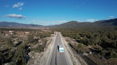 Büyük bir Amerikan beyaz kuş karavanı kırsal bir dağ aracı boyunca sürüyor. Yüksek kalite 4k görüntü