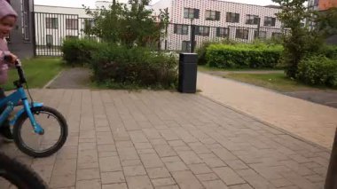 Üçüz kız kardeşler sonbaharda bahçede bisiklet sürerler. Yüksek kalite 4k görüntü