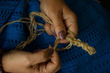 Bir kadının elleri, jüt ipliği ve örgü deseninin bir parçası. Doğal eko örgü, zanaat ve hobi, ekolojik ev dekorasyonu..