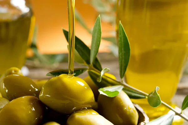 green olives and olive oil on a wooden table