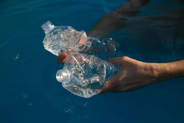 Kadınların elleri denizde plastik bir şişe taşır, plajda her gün geri dönüşüm yapar.