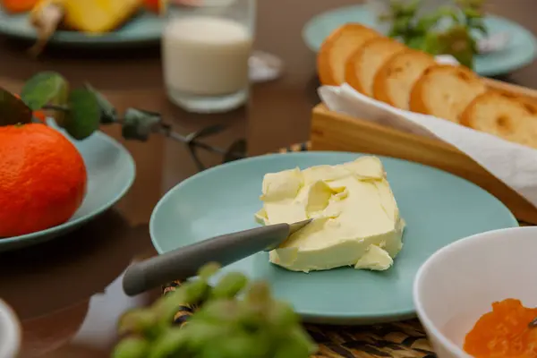 Kahvaltı masasına yakın çekim, tereyağı, ekmek, meyve ve süt, hepsi de tadını çıkarmaya hazır. Davetkar ve iştah açıcı