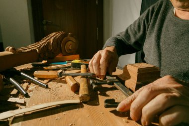 Bir zanaatkar, çeşitli aletler kullanarak ahşabı dikkatlice şekillendirir, bir atölyede geleneksel zanaatkarlık sergiler..