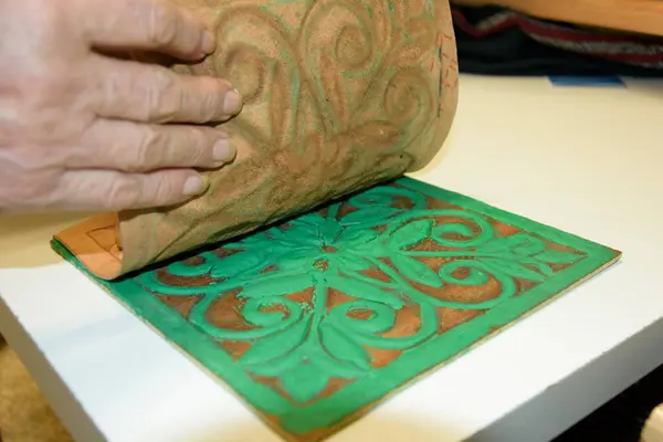 Erkek eli, tahtanın üzerindeki kabartmalı deriyi eski guadametikalar gibi altında mankenlik kiliyle hazırlıyor..