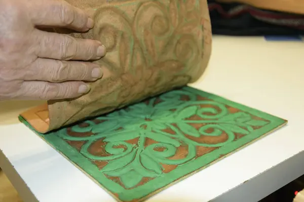 Erkek eli, tahtanın üzerindeki kabartmalı deriyi eski guadametikalar gibi altında mankenlik kiliyle hazırlıyor..