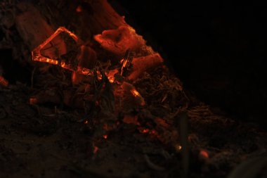 Sıcak bir şöminede parlayan közlerin yakın görüntüsü, sıcaklığı, rahatlığı ve sükuneti gösteriyor.