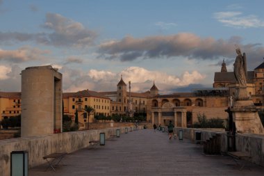 Çarpıcı bir manzara, alacakaranlık gökyüzünün altındaki antik bir şehre zarif bir şekilde bağlanan tarihi bir köprüyü sergiliyor.