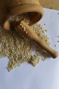 Kaba bir sahne, ahşap bir havandan akan susam tohumlarını tasvir eder. Aşçılık için mükemmeldir.