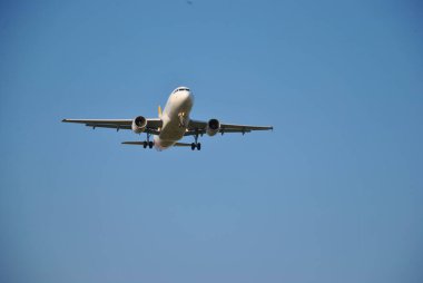 Bir uçak zarif bir şekilde açık mavi gökyüzüne doğru iniyor ve havacılığın güzelliğini en iyi şekilde gözler önüne seriyor.