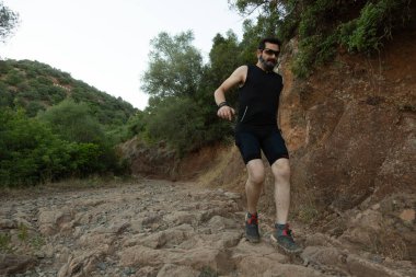 A man descends a steep path surrounded by lush greenery, embodying outdoor adventure and fitness spirit clipart