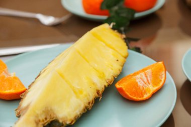 Enfes bir turkuaz tabakta sergilenen sulu ananas dilimleri ve taze turuncu segmentler.