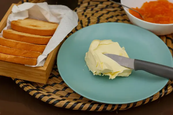 Nefis bir kahvaltı sahnesi, yağlı, çıtır çıtır tost, ve sıcak bir tabakta renkli reçel.