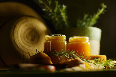 Doğal elementler ve bereketli yeşilliklerle özenle düzenlenmiş bal kavanozlarıyla estetik olarak tatmin edici bir görüntü.