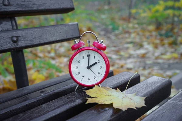 秋天公园的闹钟在长椅上 时间的流逝与季节的变化 — 图库照片