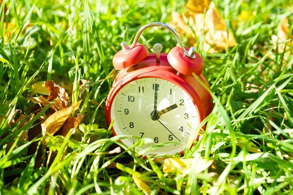 时间变了 外面的草地上挂满了秋天的黄色叶子 是经典的红色闹钟 — 图库照片