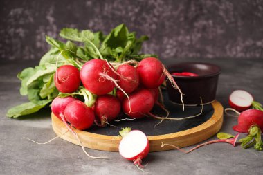 Gri zemin üzerinde yaprakları olan taze kırmızı turp..