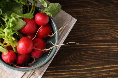 Fresh red radish in bowl on wooden background, space for text. Top view.