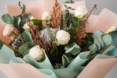 Beyaz güller, protea, esmer ve okaliptüs dallı güzel bir buket. Yakın plan..