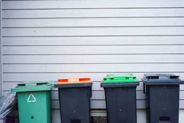 Ayrı atık toplama için farklı renklerde kapaklı bir sıra çöp kutusu: plastik, kağıt, cam, organik atık ve genel çöp. Geri dönüşüm, sürdürülebilirlik ve çevre dostu atık yönetimi kavramı.
