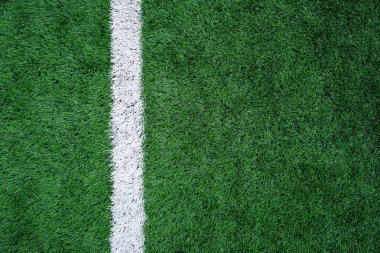 Yeşil yapay çimenlikteki beyaz bir çizginin yukarıdan aşağı görüntüsü. Futbol veya spor sahaları için tipik işaretleme, spor veya tasarım geçmişi için mükemmel.