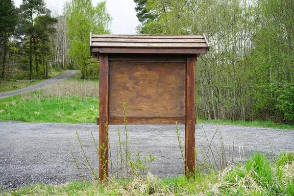 Doğal park ortamında içi boş ahşap tabela. Ağaçlar ve çakıl yollarıyla çevrili, halka duyuru ve haritalar için hazır..
