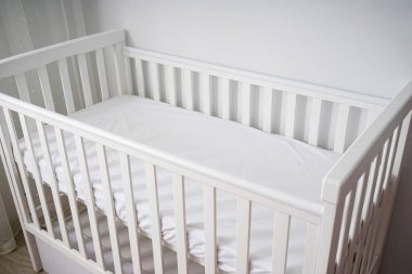Minimalist, parlak bir bebek odasına yerleştirilmiş, temiz, modern, minimalist bir bebek beşiği. Bebekler için rahat ve güvenli bir uyku ortamı.