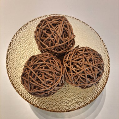 Kahverengi cam bir vazo ve ahşap bir yuva şeklindeki üç topun içinde üst görünümü olan fotoğraf..