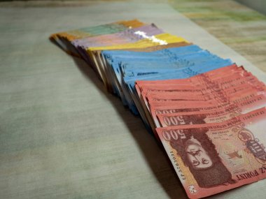 Tahta bir masanın üzerindeki bir avuç banknotun yakın çekimi.