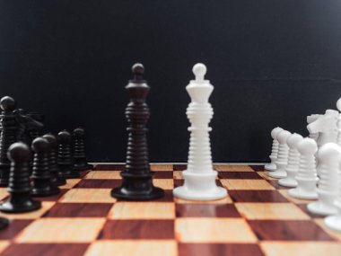 Siyah arkaplanda satranç taşları olan satranç tahtası oyunu.