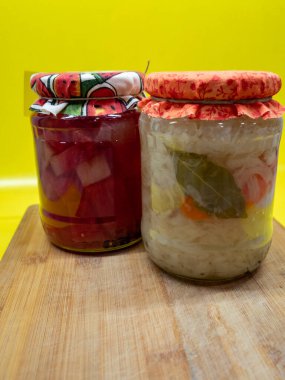 Beyaz kasede kırmızı ve sarı biberli ve havuçlu cam salatalık kavanozu..