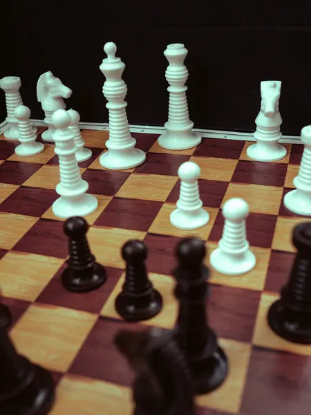 Siyah arkaplanda satranç taşları olan satranç tahtası oyunu.