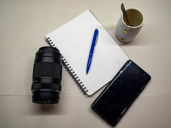 Bir kalem, kahve ve masanın üzerinde akıllı telefon olan bir defter..