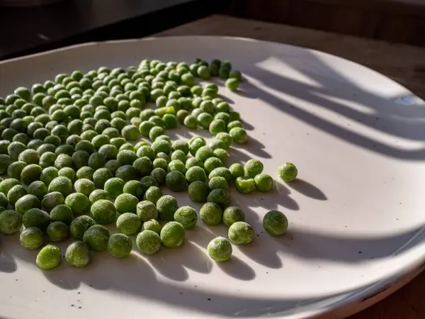 Beyaz tabakta yeşil bezelyeler