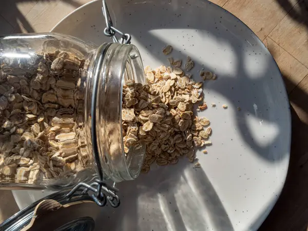 Tahta kaşıkta yulaf ezmesi ve beyaz arka planda kaşık olan bir kase.