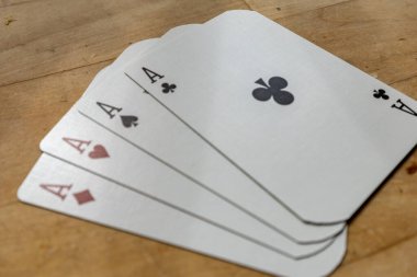 Tahta bir masada kağıt oynayan dört as.