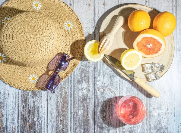 stock image Orange juice in glasses with ice, straw hat and sunglasses on white table, concept of vocation and summer.