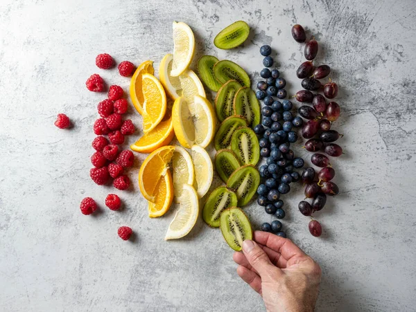Fruit cut and arranged in the order of the colors of the rainbow. One hand places the fruit in order.