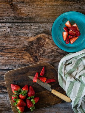 Çilek arkaplanı. Tahtada bıçakla pişirmek için olgun çilekler. Mesaj için yer var. Üst Manzara. Düz tasarım