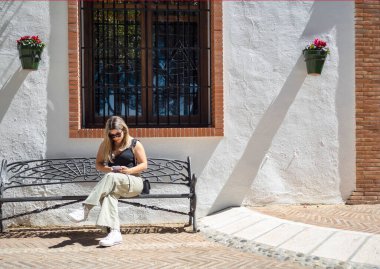 İspanya 'nın Costa del Sol kentindeki bir turist kasabasında bir bankta oturan kız cep telefonuna bakıyor..