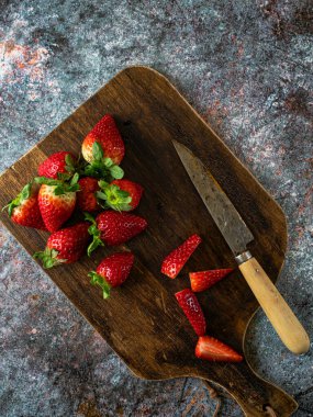 Çilek arkaplanı. Tahtada bıçakla pişirmek için olgun çilekler. Mesaj için yer var. Üst Manzara. Düz tasarım