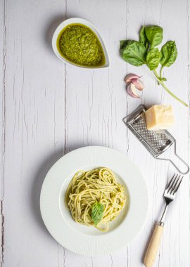 Taze ev yapımı pesto soslu İtalyan spagettisi. Beyaz bir tahtanın üzerinde yenmiş..
