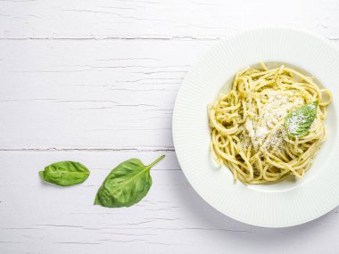 Taze ev yapımı pesto soslu İtalyan spagettisi. Beyaz bir tahtanın üzerinde yenmiş..