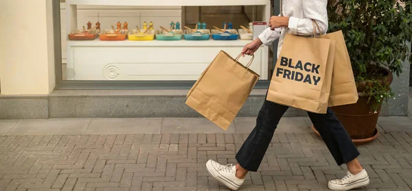 Alışveriş çantalı genç bir kadın bir mağazanın önünde yürüyor. Malaga Belediye Başkanı Plaza. Kara Cuma satışları