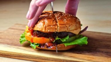 Hamburger, tahta bir tahtanın üzerinde ikiye bölünmüş. Sulu et, taze domates, gevrek marul ve erimiş peynir.. 